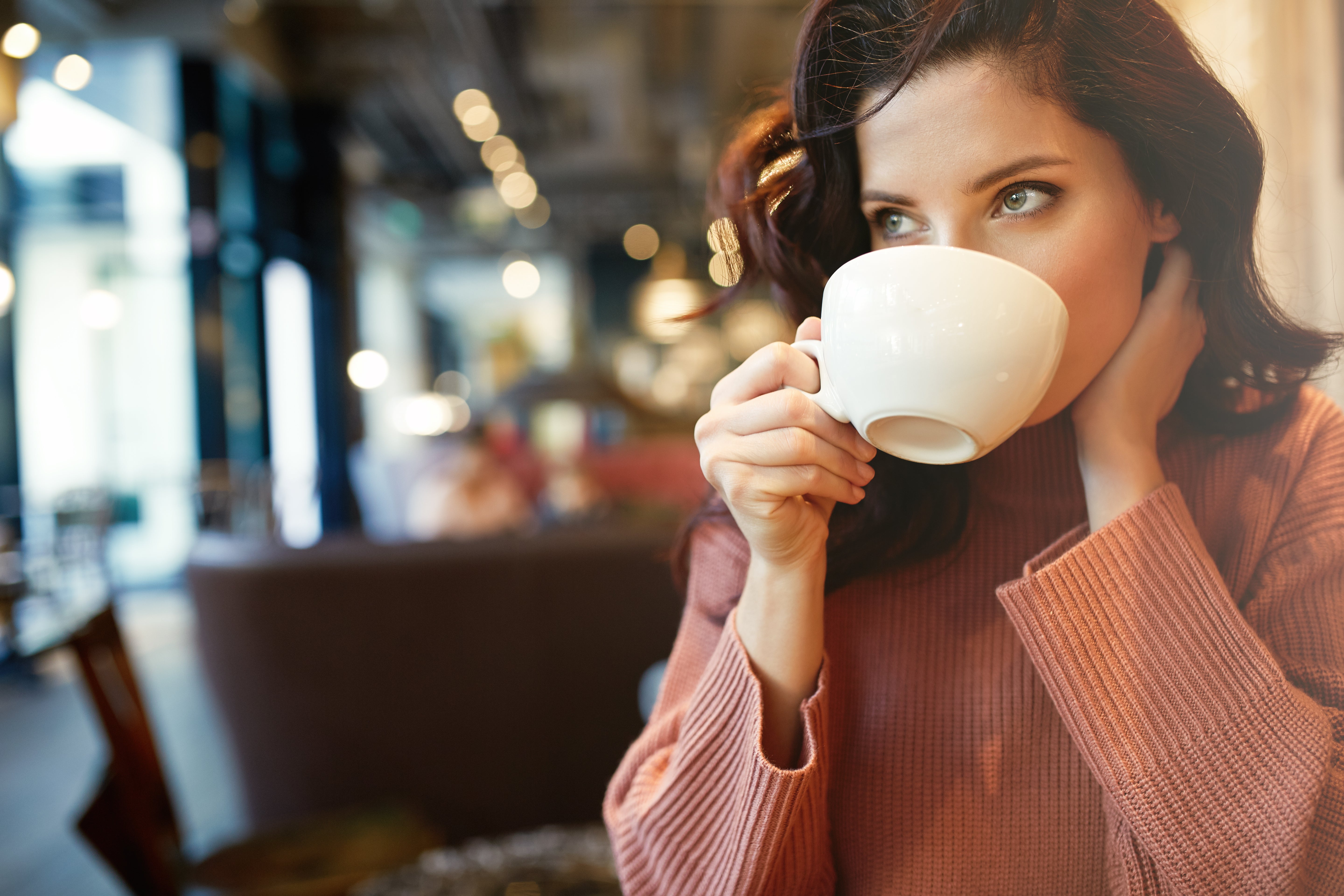 Women siping a white mug in a cafe